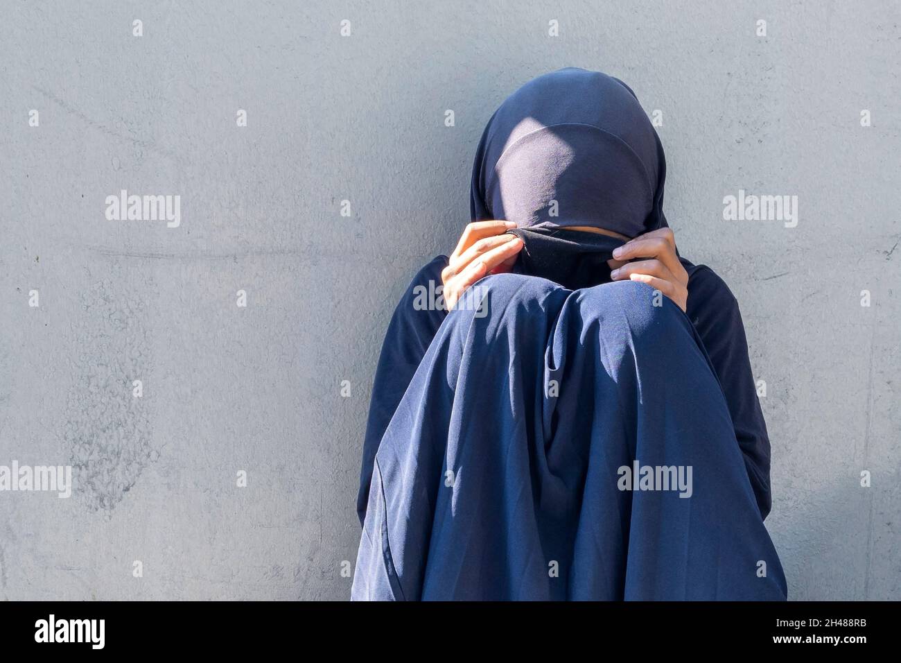 Fille musulmane, femme assise dans une rue de la ville.Femme pauvre musulmane à visage fermé mendiant pour les aumône. Banque D'Images