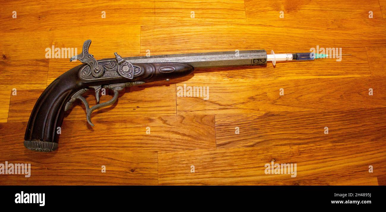 Vue de dessus d'un ancien pistolet en forme de flatlock chargé d'une seringue de vaccin sur une table en bois Banque D'Images