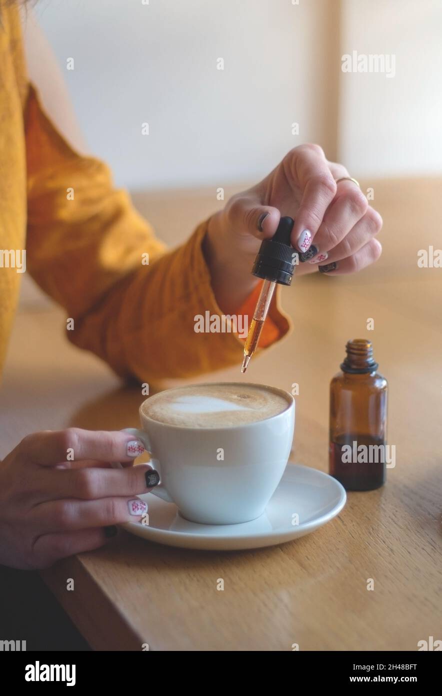 Femme utilisant des plantes de cannabis dans des boissons.Ajouter de l'huile de CBD dans une tasse de café.le concept de l'utilisation de la marijuana médicale. Banque D'Images