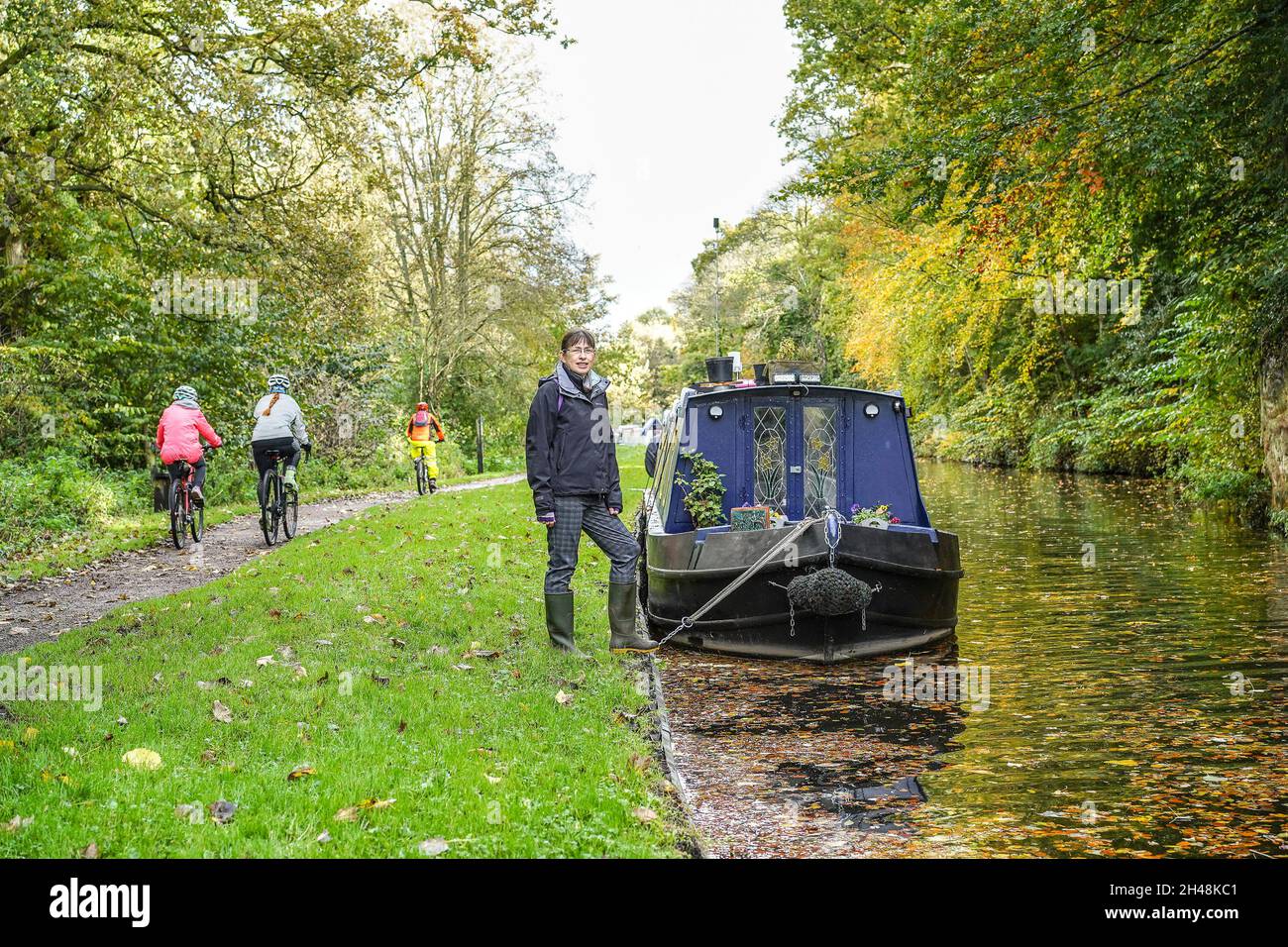 Vue de face d'une femme qui marche sur un bateau à rames pendant que les cyclistes passent sur le sentier en automne. Banque D'Images