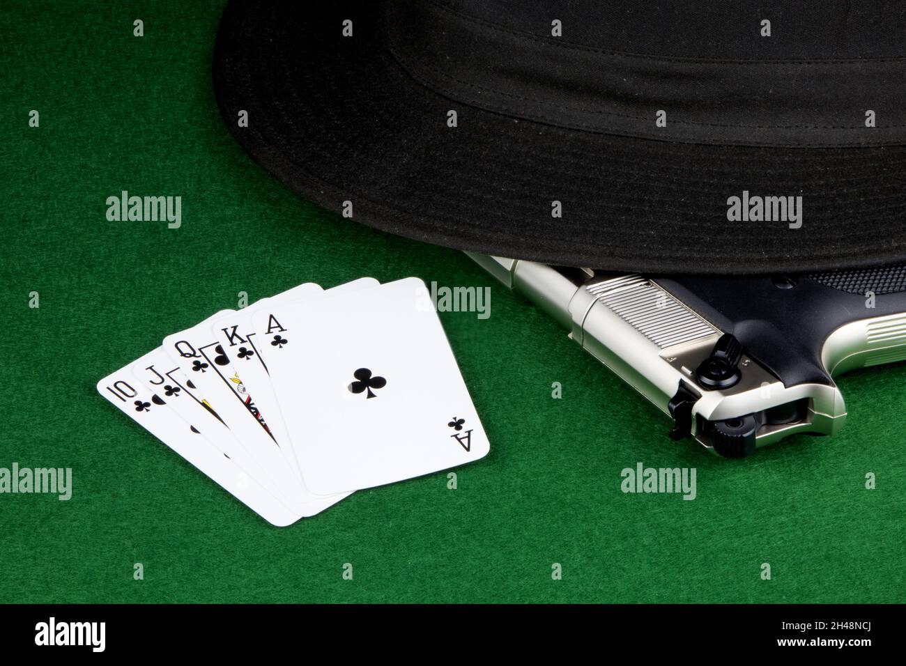 Cartes à jouer avec un pistolet et un chapeau sur une table de jeu recouverte de feutre Banque D'Images