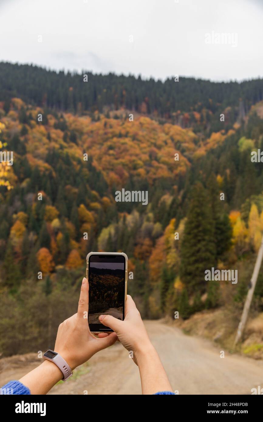Femme prenant des photos sur son smartphone de forêt de montagne et d'automne.Couleurs d'automne. Banque D'Images