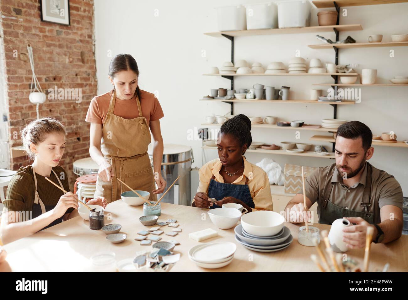 Photo à tons chauds d'un groupe diversifié de personnes décorant des céramiques dans un atelier de poterie Banque D'Images