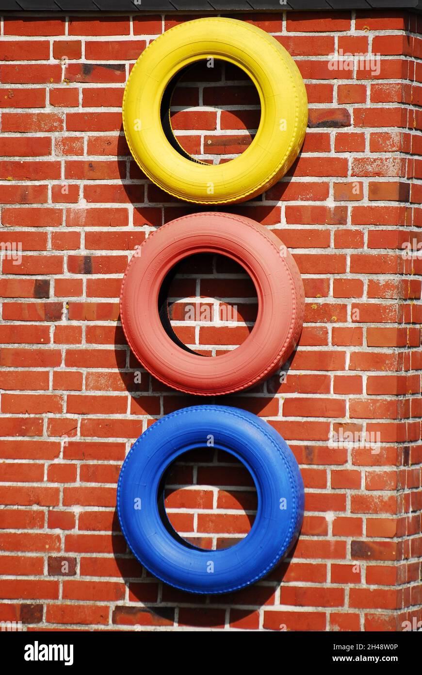 Le monde est coloré, même à travers trois pneus de couleur sur le mur de la maison. Banque D'Images