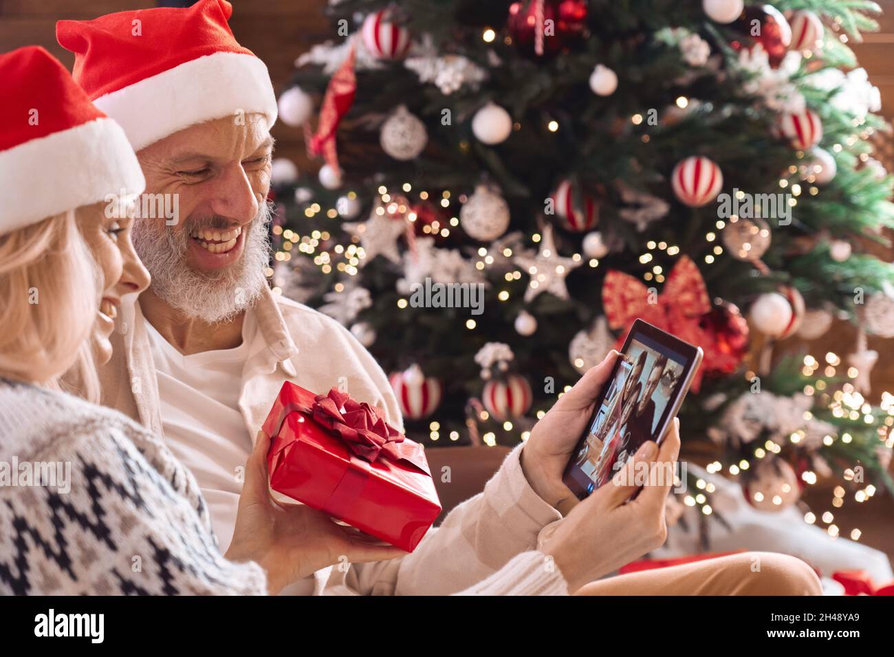 Joyeux grand-parents, vieux couple, saluant la famille lors de l'appel vidéo de Noël. Banque D'Images