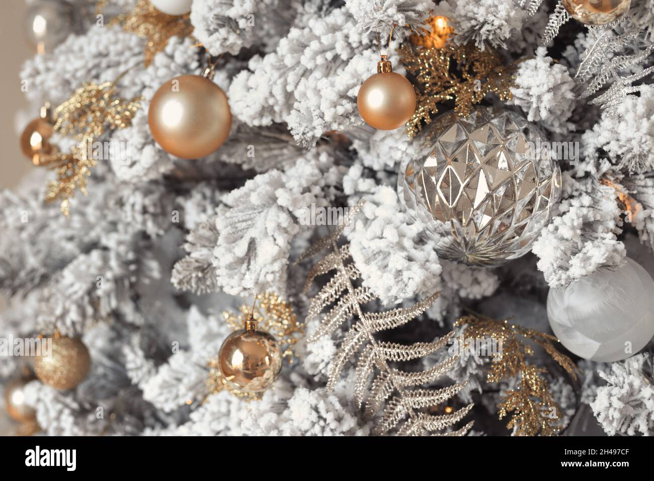 Gros plan sur une photo de balles de jouet en argent et or sur un sapin de Noël enneigé de luxe à la mode Banque D'Images Gros plan sur une photo de balles de jouet en argent et or sur un sapin de Noël enneigé de luxe à la mode Banque D'Images