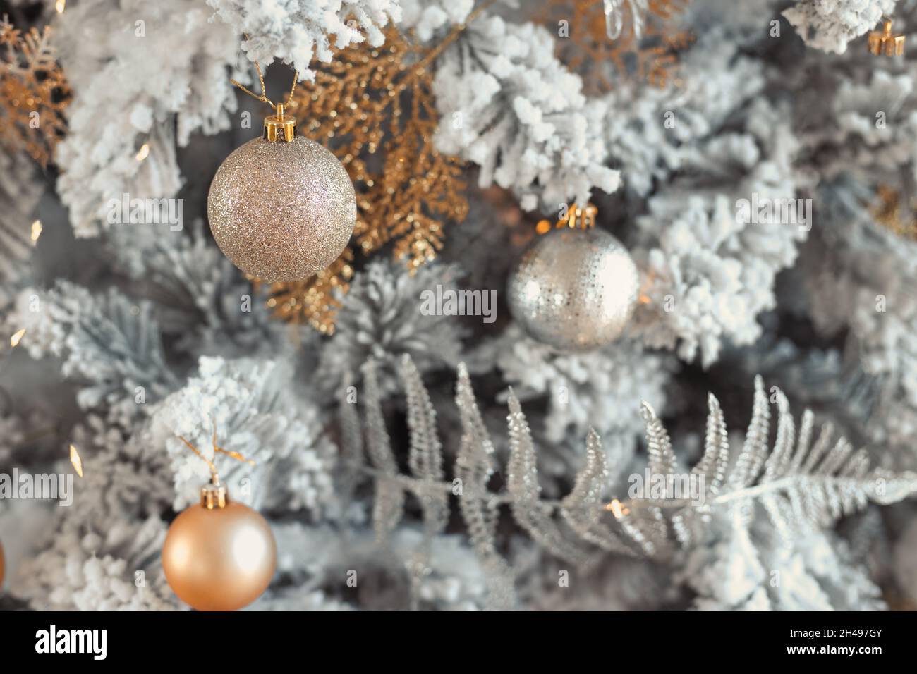 Gros plan sur une photo de balles de jouet en argent et or sur un sapin de Noël enneigé de luxe à la mode Banque D'Images Gros plan sur une photo de balles de jouet en argent et or sur un sapin de Noël enneigé de luxe à la mode Banque D'Images