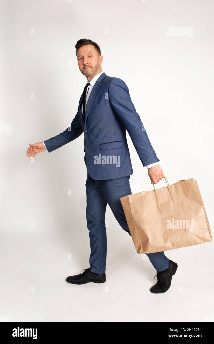 Homme d'affaires en costume marcher avec sac en papier d'artisanat dans la main, matériel de recyclage, achats, rabais et vente, modèle,Service de livraison.Studio tourné sur W Banque D'Images