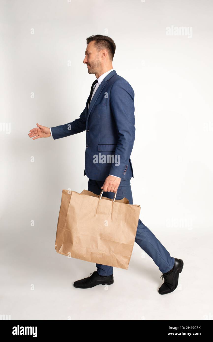Homme d'affaires combinaison avec cravate marche avec sac en papier d'artisanat dans la main, matériel de recyclage, achats, remise et vente, modèle,Service de livraison.Studio Banque D'Images