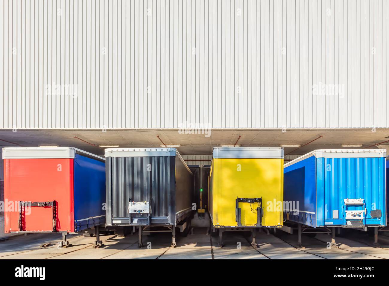 Remorques rouges, noires, jaunes et bleues devant le quai de chargement d'un entrepôt néerlandais Banque D'Images