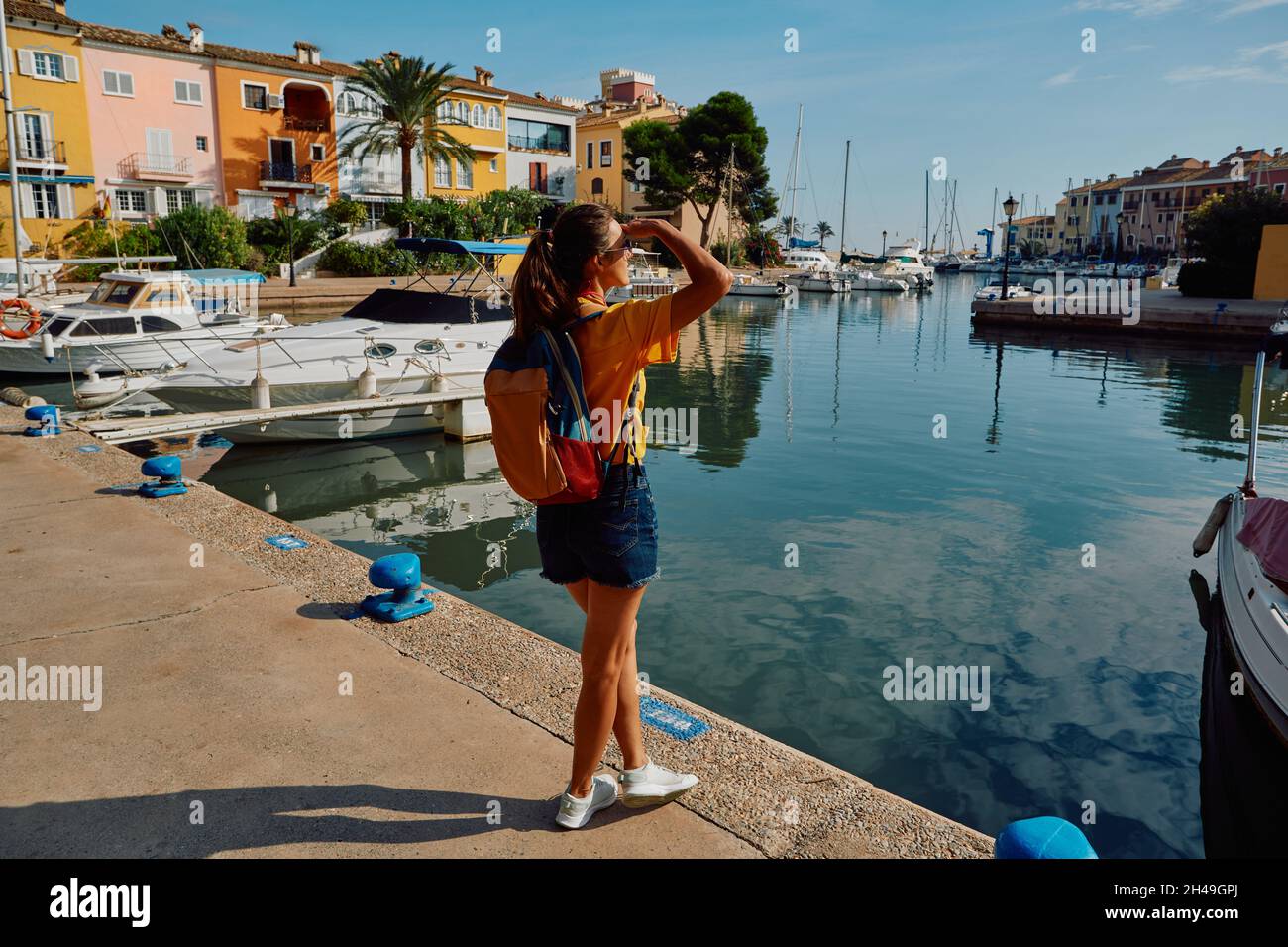 Femme voyageuse se tient sur la jetée avec des yachts et des bateaux dans le beau port de Port Saplaya près de Valence avec des maisons colorées. concept de voyageur Banque D'Images