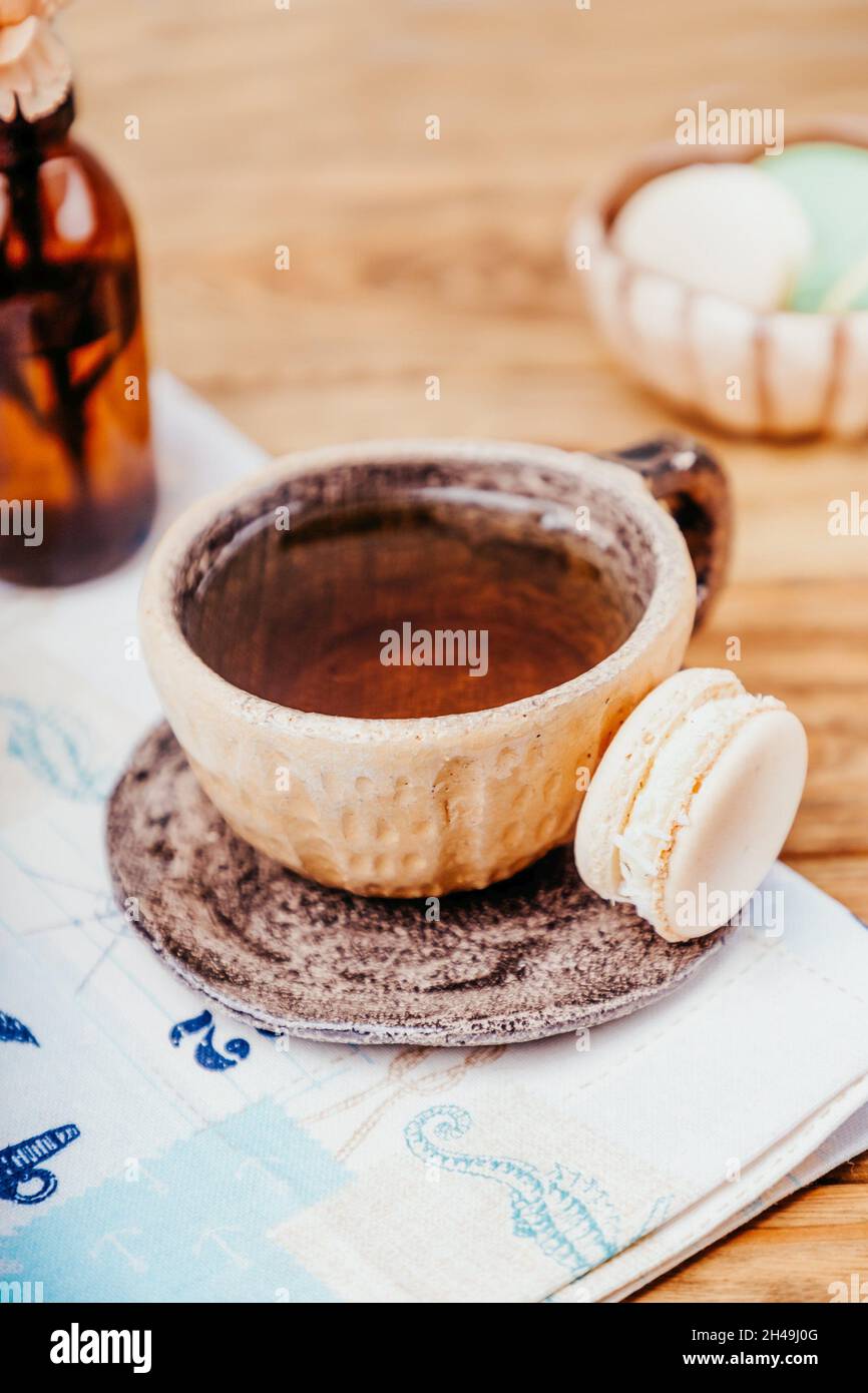 Tasse en céramique avec thé et macaron sur une table en bois, espace copie Banque D'Images