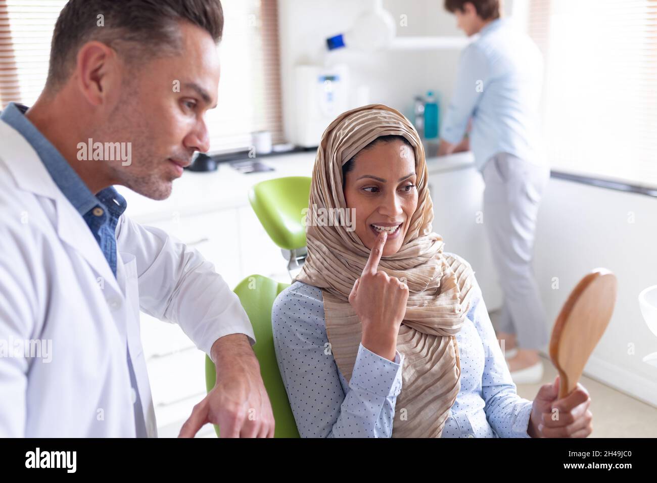 Un dentiste de sexe caucasien examine les dents d'une patiente dans une clinique dentaire moderne Banque D'Images