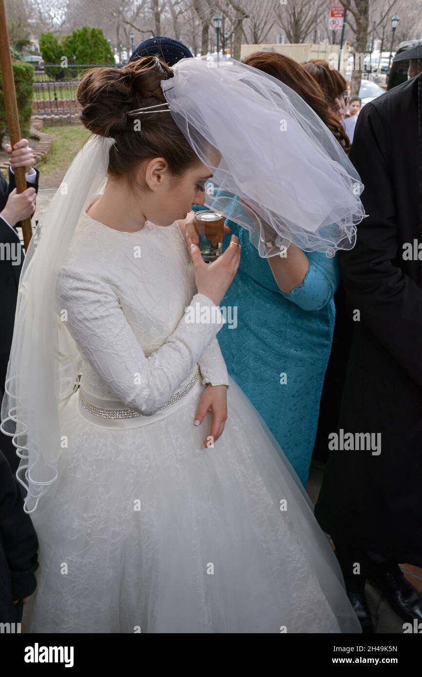 Une mariée juive orthodoxe boit une gorgée de vin sous un chuppah pendant sa cérémonie de mariage.À Brooklyn, New York. Banque D'Images