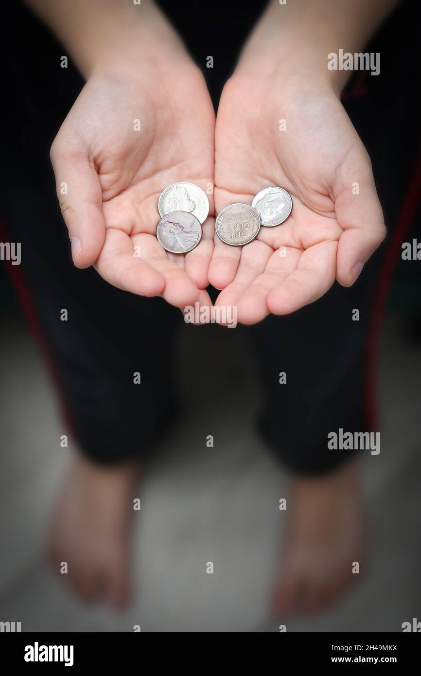 Les mains pliées d'un garçon de huit ans mendiant avec peu des centimes Banque D'Images