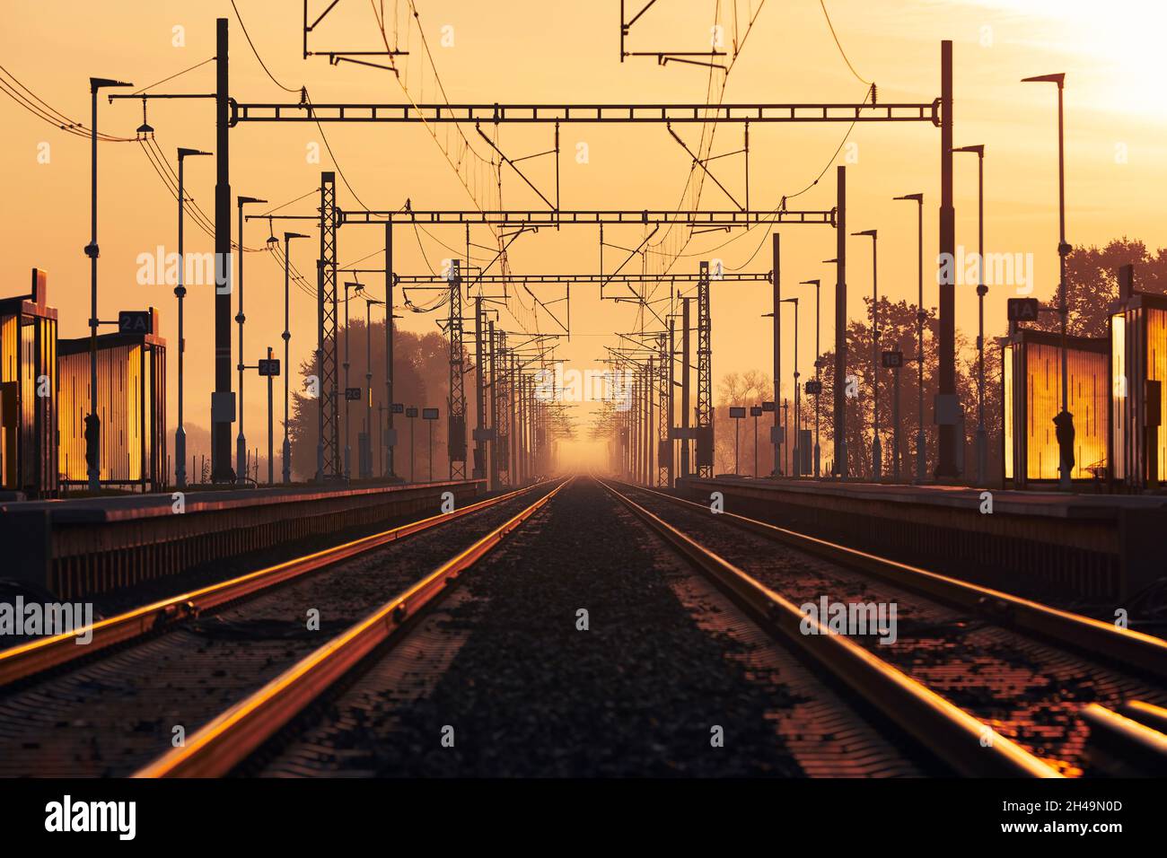 Chemin de fer au lever du soleil doré.Perspective décroissante de deux voies ferrées vides dans la gare. Banque D'Images