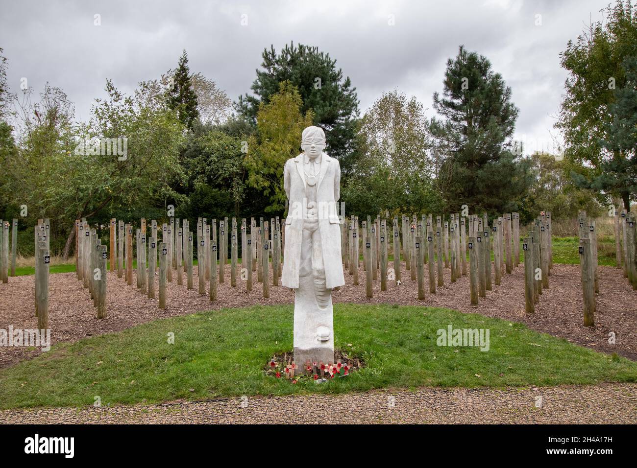 Le mémorial « Hot at Dawn » au National Memorial Arbouretum, Staffordshire, Royaume-Uni.Une statue d'un jeune soldat britannique représente le Soldat Herbert Burden, l'un des hommes abattus à l'aube de la première Guerre mondiale pour avoir enfreint les règles.Aujourd'hui, nous comprenons que beaucoup de ceux qui ont été exécutés souffraient probablement de stress de combat.C'était connu sous le nom de 'Shell Shock' en 1917, mais n'a pas été vraiment compris jusqu'à plus récemment.La statue a été sculptée par Andy DeComyn.Les piquets en bois se trouvent dans un demi-cercle contenant les noms de certains de ceux qui ont été tués de cette façon. Banque D'Images