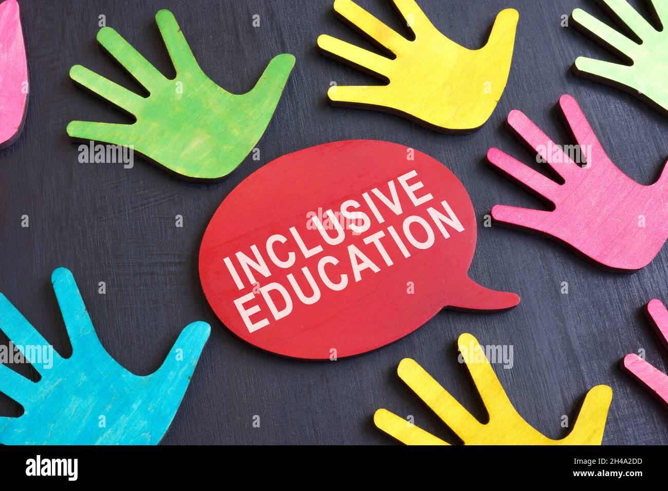 Concept d'éducation inclusive.Palmiers multicolores sur une surface sombre et une inscription. Banque D'Images