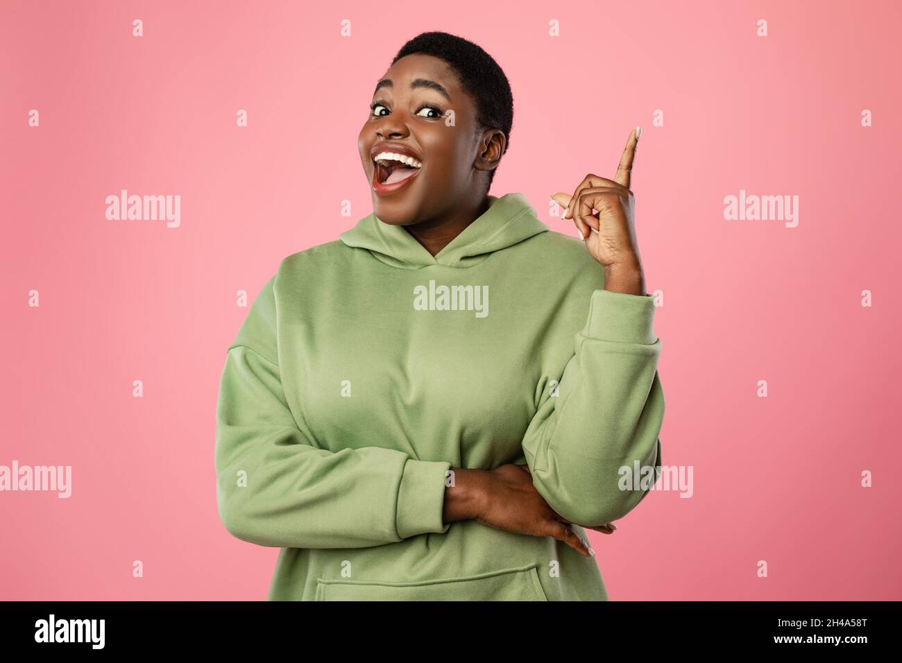 Bonne idée.Excitée femme africaine américaine obèse pointant du doigt vers le haut avoir le moment Eureka et l'inspiration se tenant sur le fond de studio rose, souriant Banque D'Images