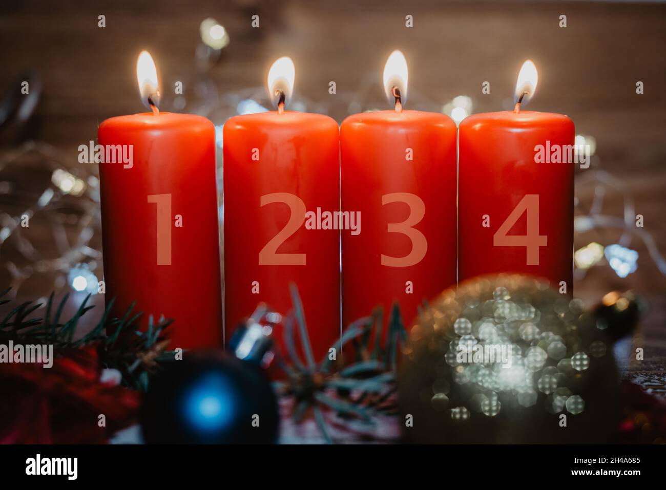 Quatre bougies de l'Avent rouges numérotées avec quatre bougies allumées et décoration de noël couchée dans la neige comme modèle Banque D'Images