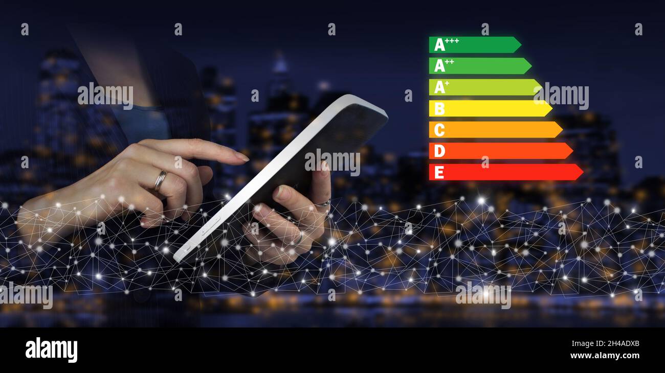Modèle de taux d'efficacité énergétique.Tablette blanche tactile avec logo d'efficacité énergétique numérique sur fond ville sombre et flou.Concept d'ecol Banque D'Images