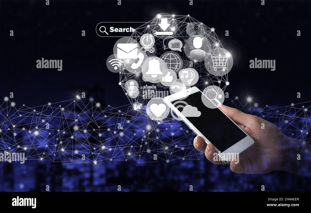 Concept de communication et de réseau.Main tenir smartphone blanc avec hologramme numérique icônes de médias sociaux signe sur la ville sombre arrière-plan flou.Social moi Banque D'Images