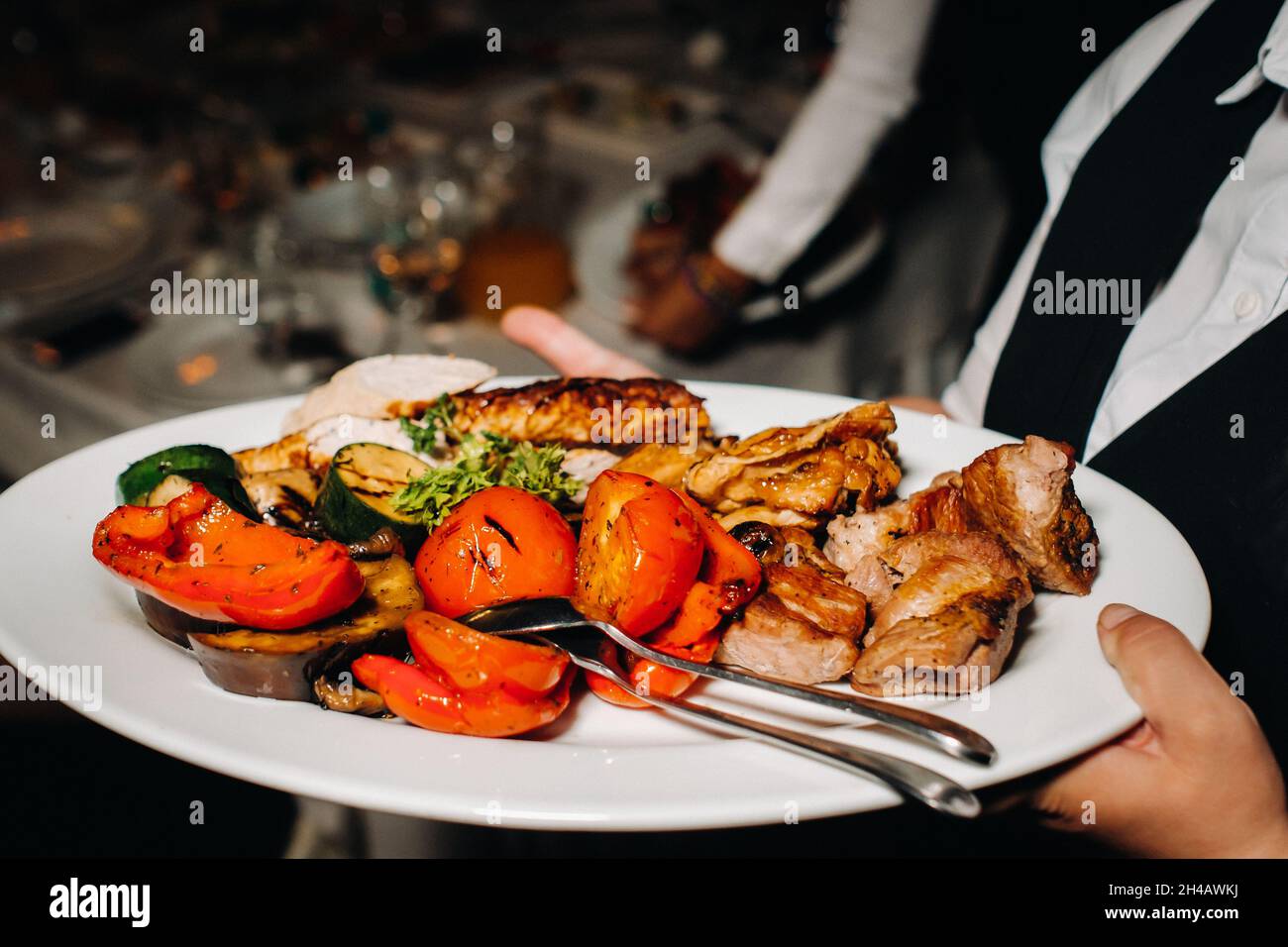 Le soir, le restaurant sert un plat chaud de barbecue avec vegetables.fried viandes avec des tomates et d'autres légumes sur une assiette dans un restaurant Banque D'Images