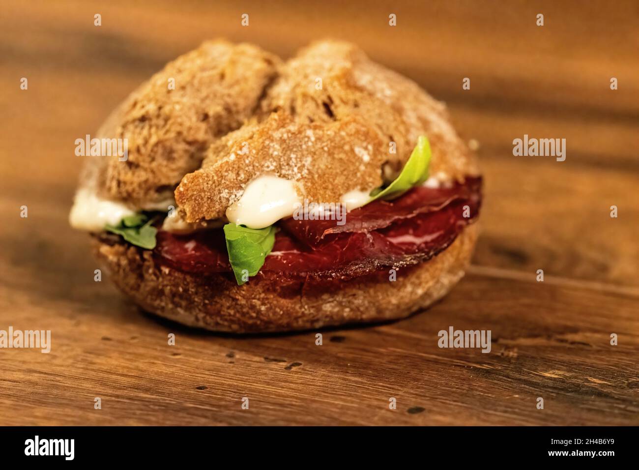 sandwich avec salami et légumes sur une surface en bois Banque D'Images