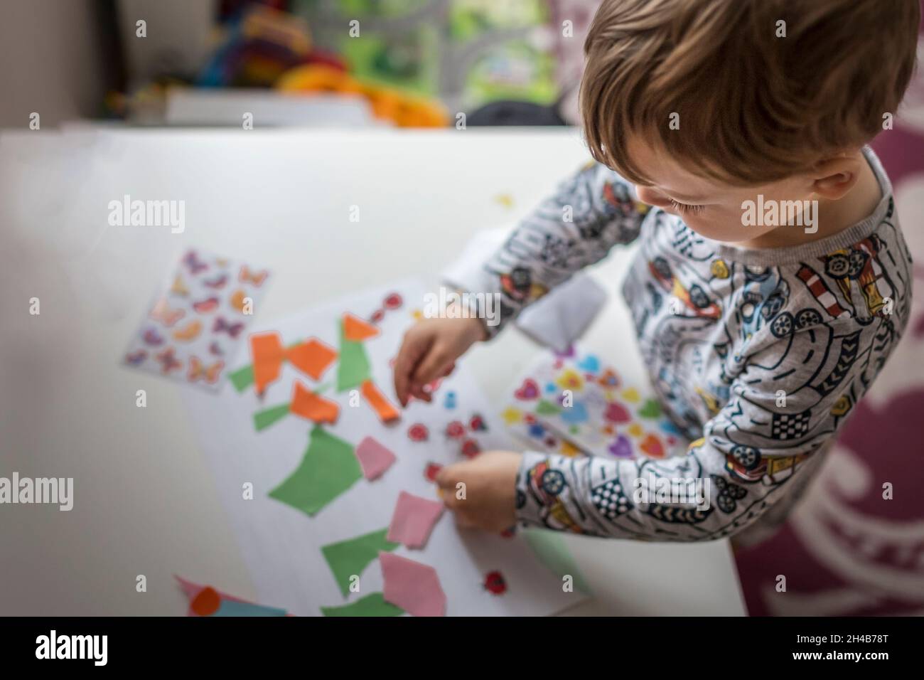 Garçon blond debout à côté de la table blanche et faisant le projet d'art Banque D'Images