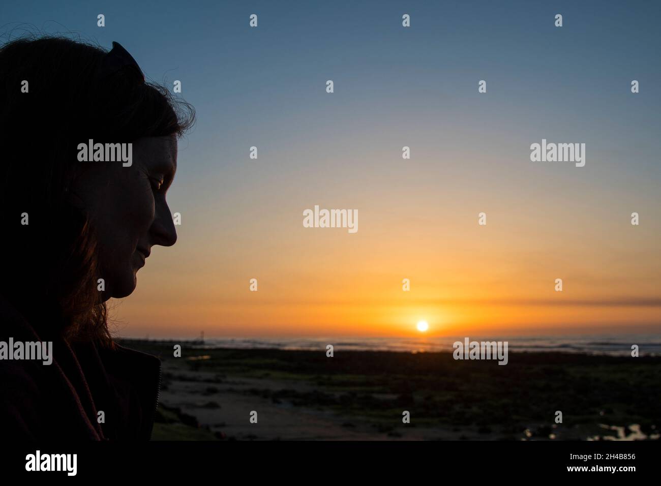 Femme et soleil se couche à West Runton Beach, sur la côte nord de Norfolk Banque D'Images