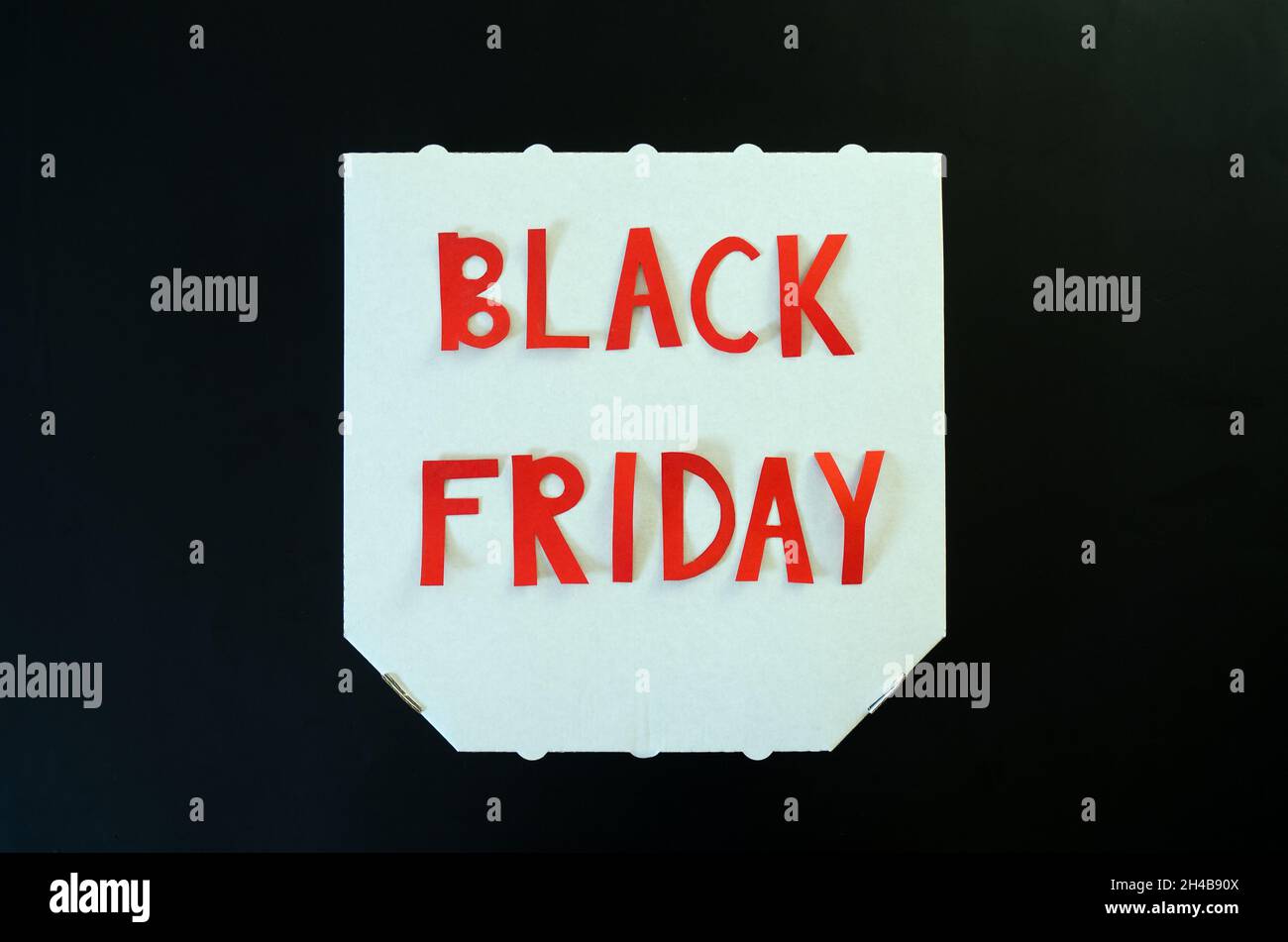 Inscription « Black friday » sur une boîte à pizza en carton blanc sur fond noir.Espace de copie, vue de dessus, Flat lay.Circulaire des fêtes créative.Vente. Banque D'Images