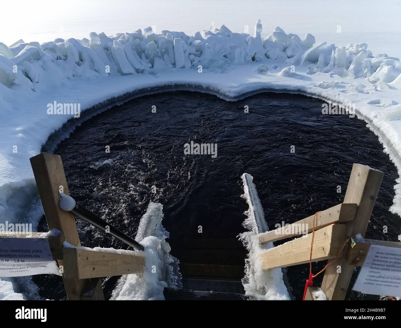 Des escaliers en bois gelés descendent dans un bain de neige.Le bain de glace renforce le corps contre le froid et les maladies.Natation sur glace Banque D'Images