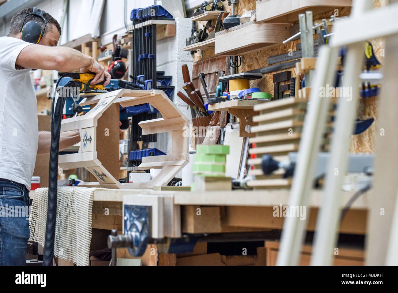 Un homme utilisant une ponceuse électrique à outils électriques pour fabriquer du bois dans le commerce de menuiserie Banque D'Images