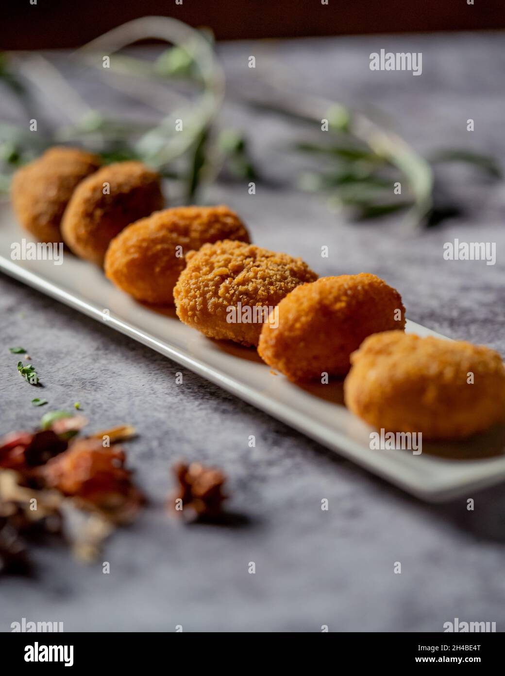 Photo verticale sélective de délicieux nuggets de poulet sur une longue assiette blanche dans un restaurant Banque D'Images