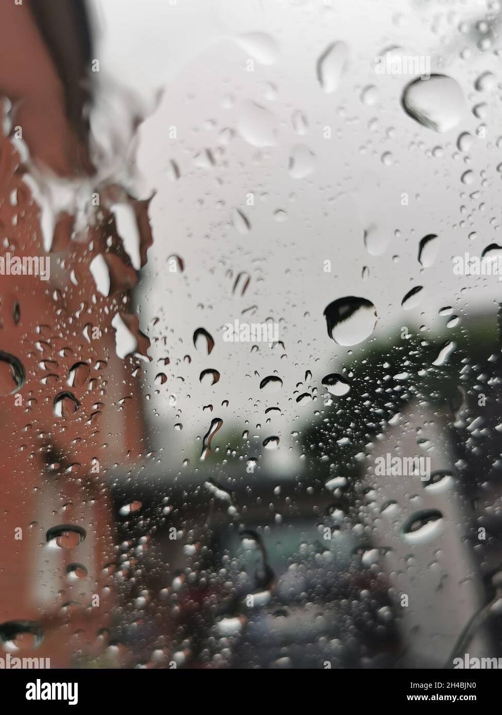 Gouttes de pluie sur une fenêtre en verre avec le fond des bâtiments. Banque D'Images