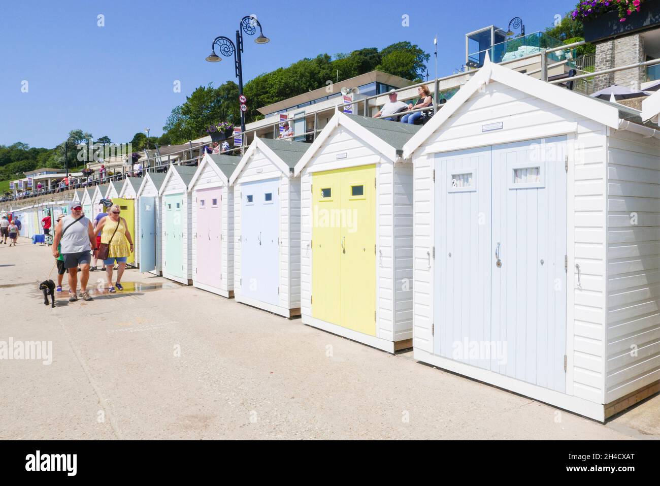 Les gens qui marchent au-delà de la couleur pastel Beach huts Lyme Regis plage Dorset Jurassic côte héritage côte Angleterre GB Europe Banque D'Images