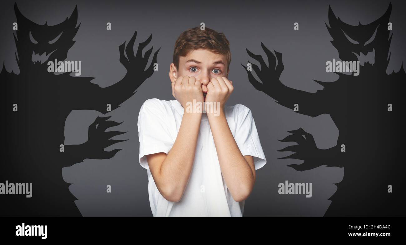 Craintes intérieures.Un garçon terrifié debout avec des monstres d'ombre dessinés autour de lui Banque D'Images