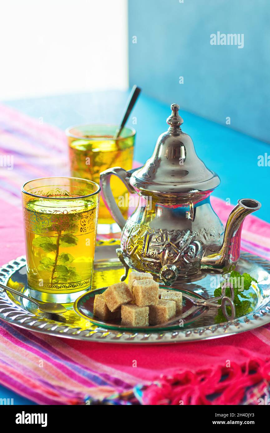 Deux verres de thé chaud à la menthe marocaine sur un plateau métallique avec un thé, de la menthe et des cubes de sucre brun Banque D'Images