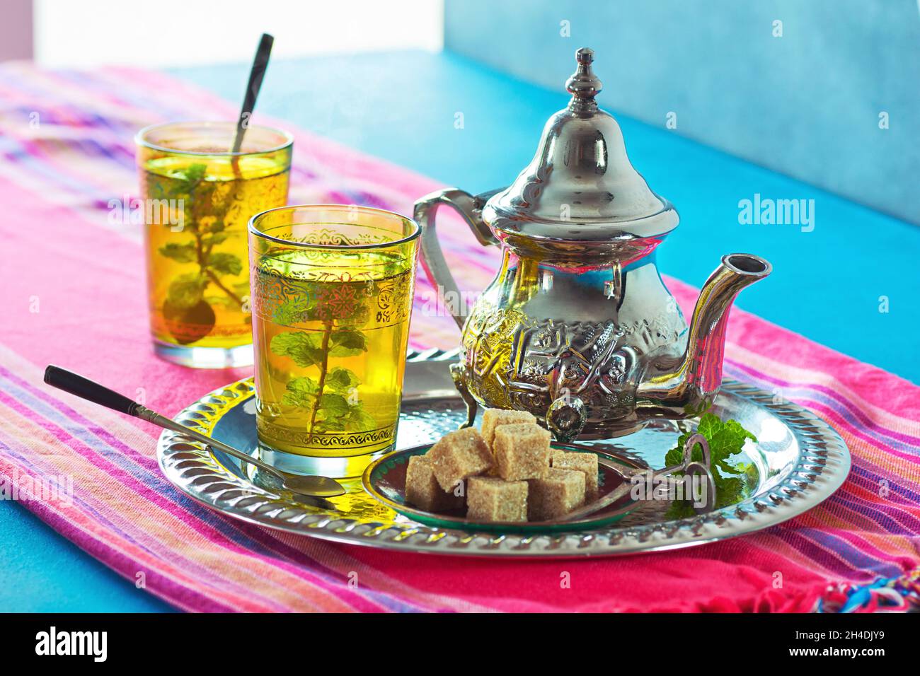 Deux verres de thé chaud à la menthe marocaine sur un plateau métallique avec un thé, de la menthe et des cubes de sucre brun Banque D'Images