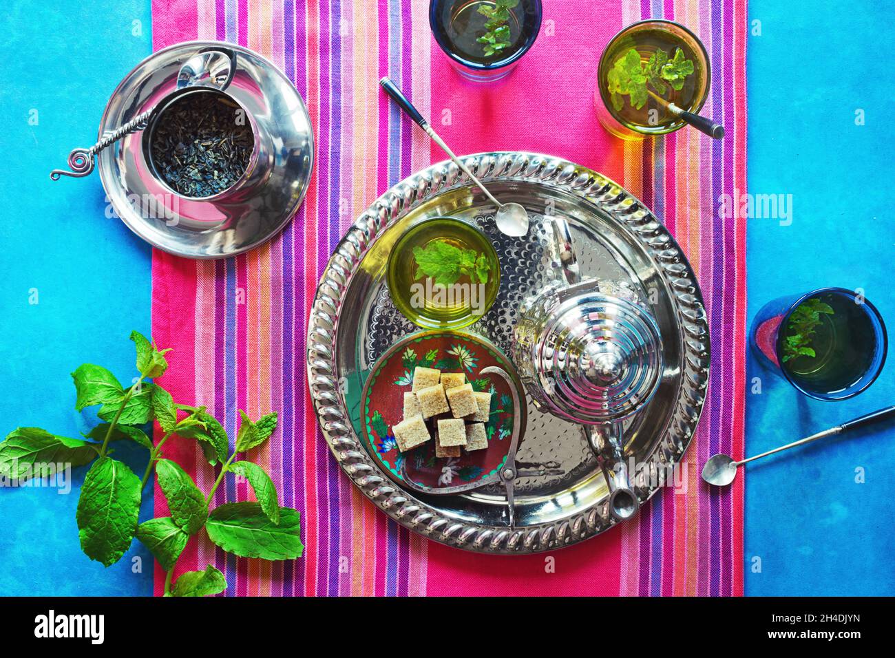 Deux verres de thé chaud à la menthe marocaine sur un plateau métallique avec un thé, de la menthe et des cubes de sucre brun Banque D'Images