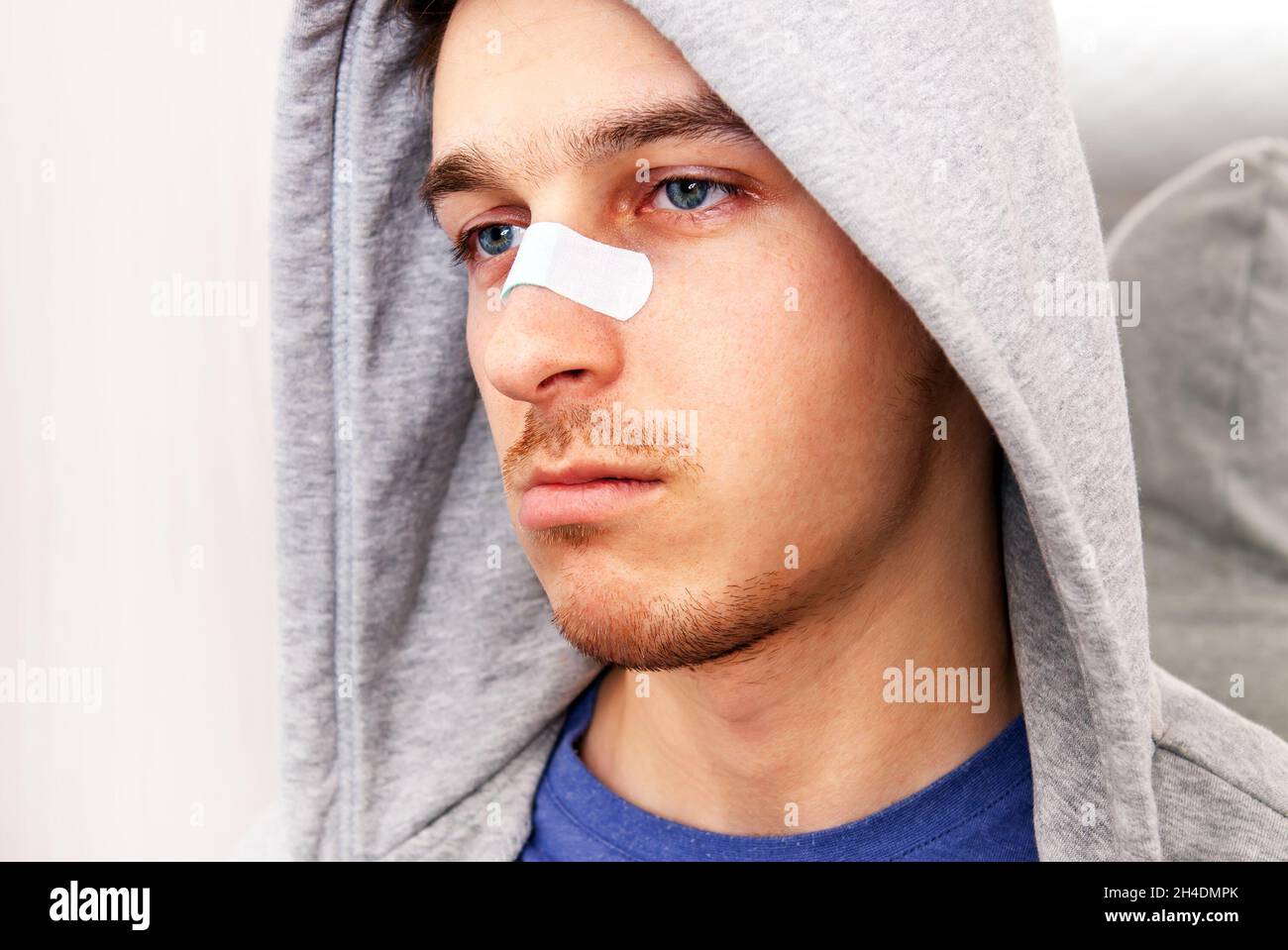 Triste jeune homme avec un plâtre collant sur le nez Portrait de gros plan Banque D'Images