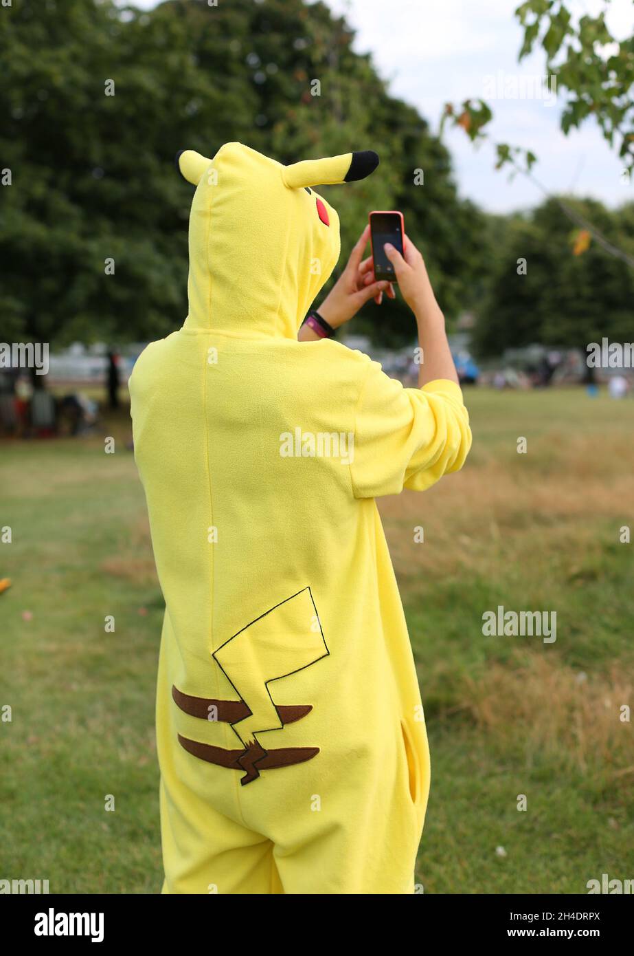 Un fan de Pokemon habillé comme personnage préféré Pikachu joue Pokemon Go sur son téléphone à Hyde Park, dans le centre de Londres, le samedi 30 juillet. Banque D'Images
