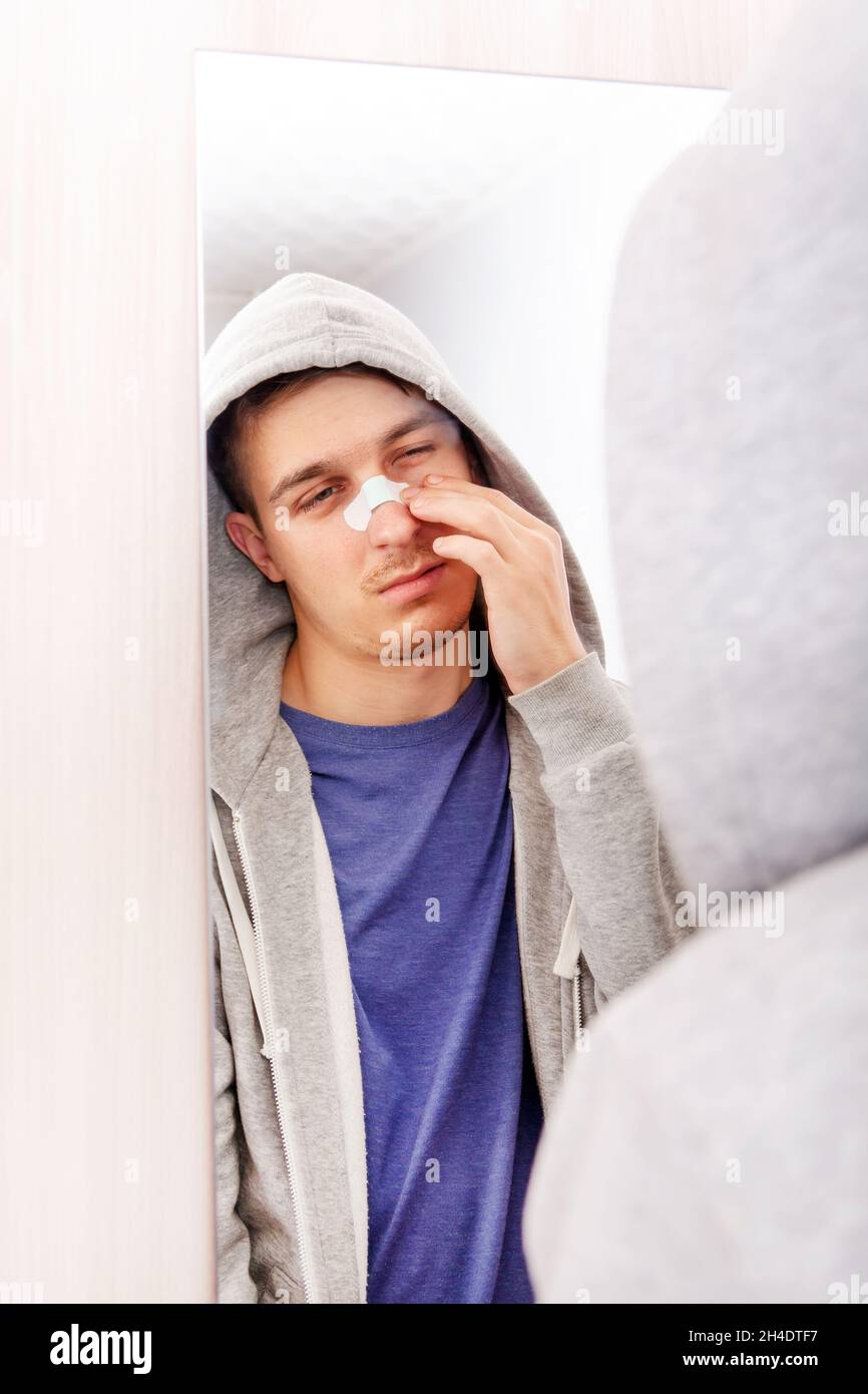 Jeune homme avec un plâtre collant sur le nez dans la chambre Banque D'Images