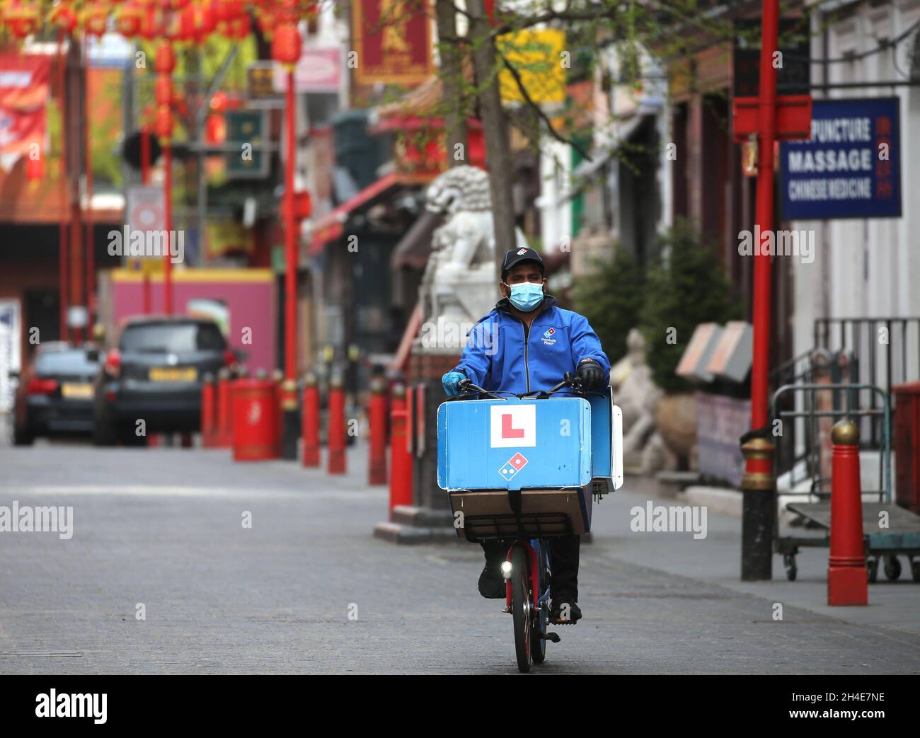 Un cycliste de la livraison de Domino's Pizza portant un masque chirurgical passe par Chinatown à Londres, tandis que le Royaume-Uni continue de se verrouiller pour aider à freiner la propagation du coronavirus.Date de publication : lundi 20 avril 2020. Banque D'Images