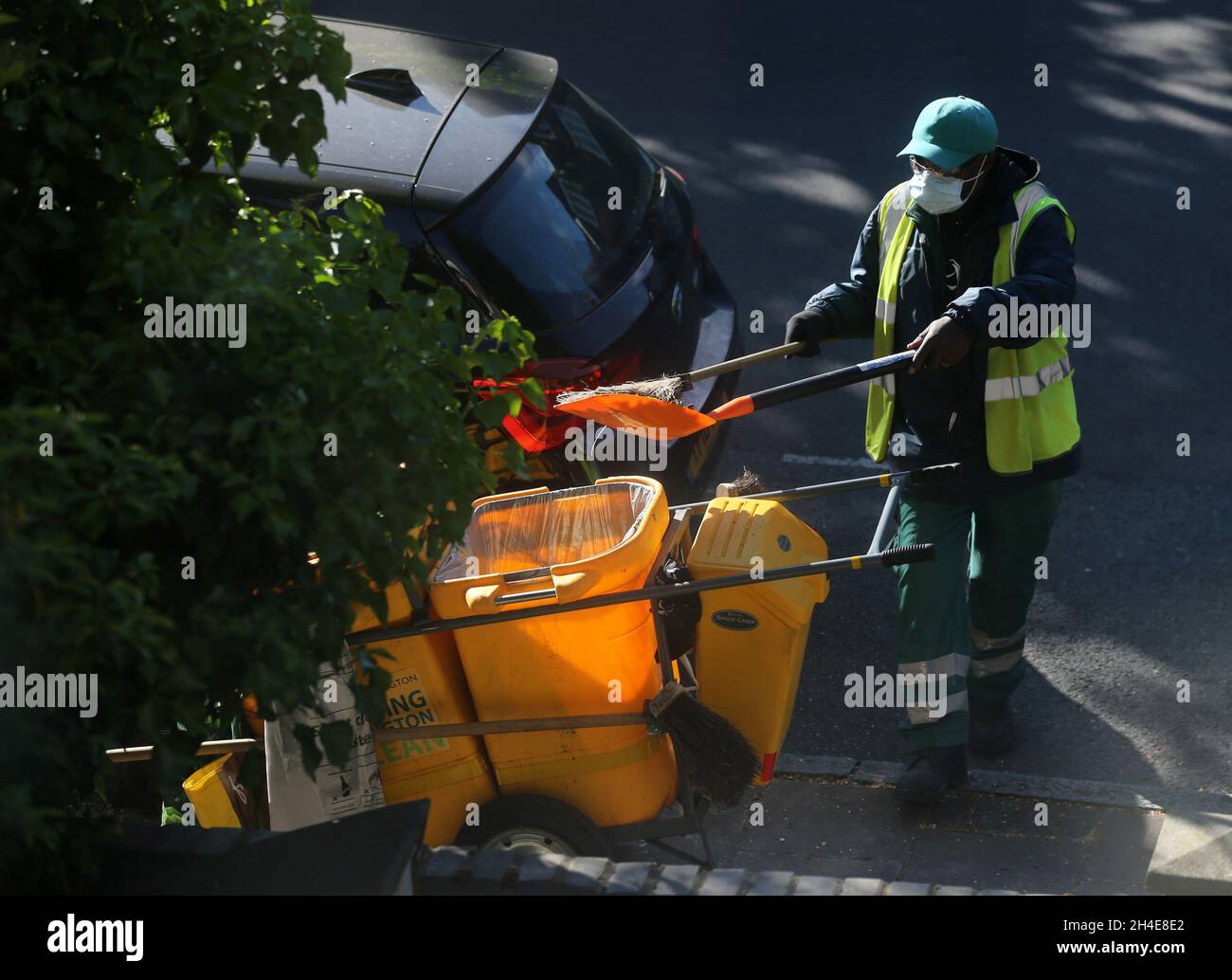 Un nettoyeur de rue portant un équipement personnel de protection (EPI) balaie une route dans le nord de Londres, après l'introduction de mesures pour mettre le pays hors de son confinement.Date de la photo: Mardi 19 mai 2020 Banque D'Images