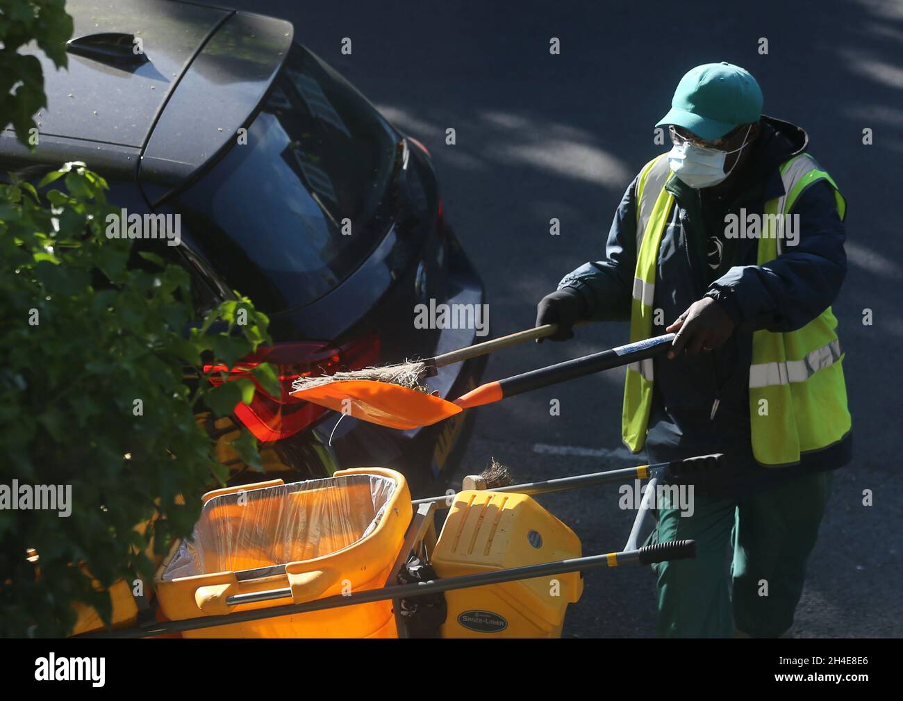 Un nettoyeur de rue portant un équipement personnel de protection (EPI) balaie une route dans le nord de Londres, après l'introduction de mesures pour mettre le pays hors de son confinement.Date de la photo: Mardi 19 mai 2020 Banque D'Images