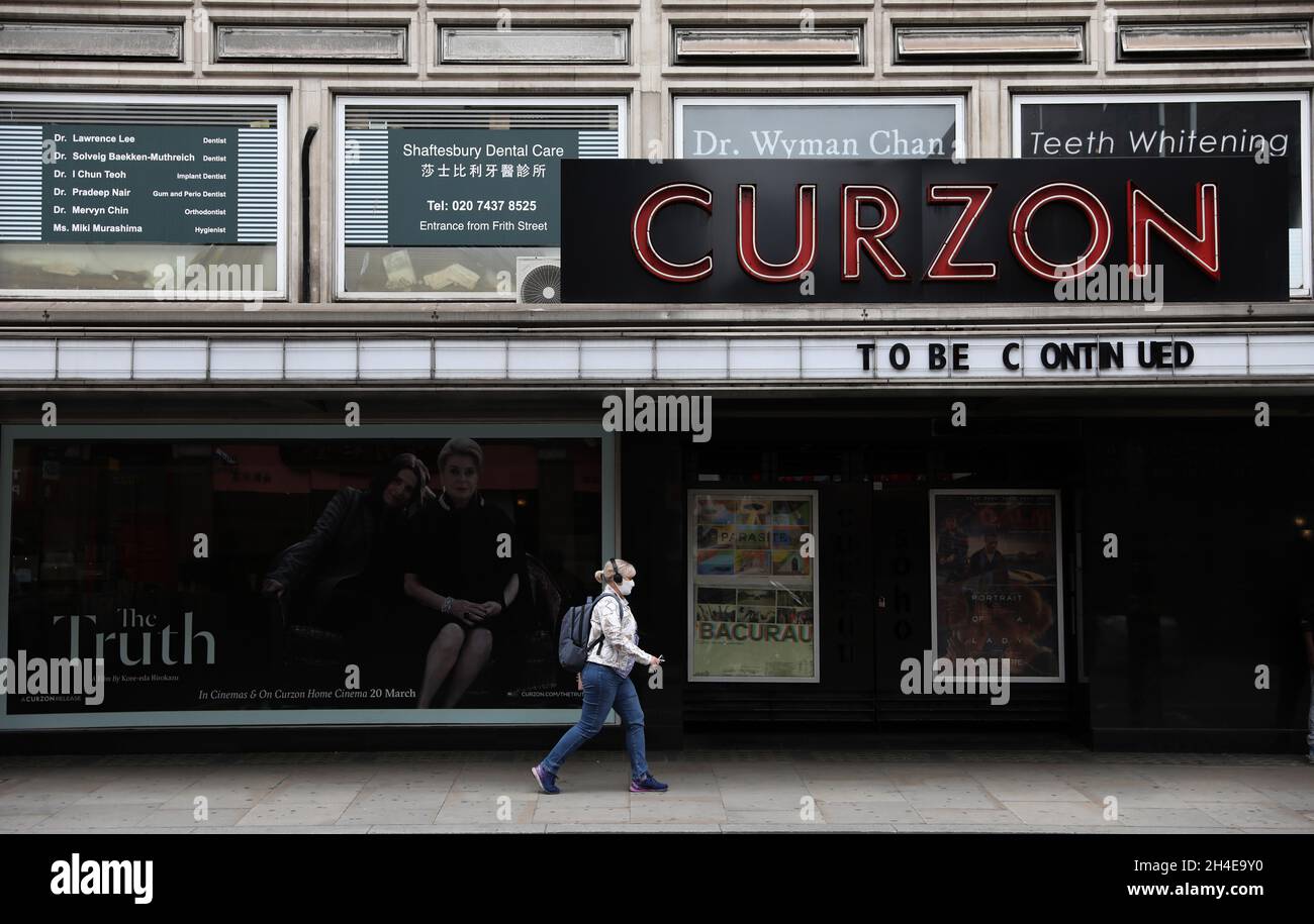 Une femme portant un masque protecteur se prompare devant un cinéma Curzon fermé à Shaftesbury Avenue à Londres. Cette semaine, le gouvernement britannique a dévoilé un « paquet de 1.57 milliards de livres sterling » destiné au secteur des arts, conçu pour aider les musées, les galeries, les théâtres, les cinémas indépendants, les sites patrimoniaux et les sites musicaux à traverser la pandémie du coronavirus. Date de la photo: Jeudi 9 juillet 2020. Banque D'Images