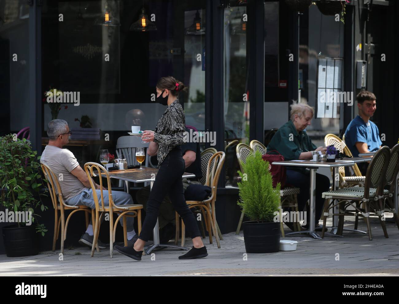 Une serveuse portant un masque facial protecteur sert les clients sur les tables à l'extérieur du restaurant français Montmartre Brasserie à Crouch End, dans le nord de Londres, après la levée de nouvelles restrictions de verrouillage du coronavirus en Angleterre. Date de la photo : dimanche 12 juillet 2020. Banque D'Images