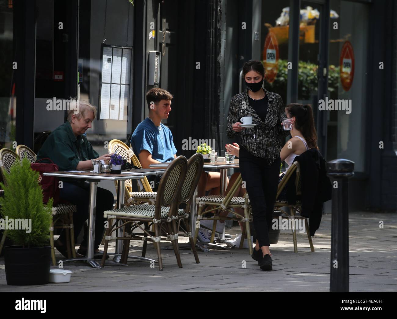 Une serveuse portant un masque facial protecteur sert les clients sur les tables à l'extérieur du restaurant français Montmartre Brasserie à Crouch End, dans le nord de Londres, après la levée de nouvelles restrictions de verrouillage du coronavirus en Angleterre. Date de la photo : dimanche 12 juillet 2020. Banque D'Images