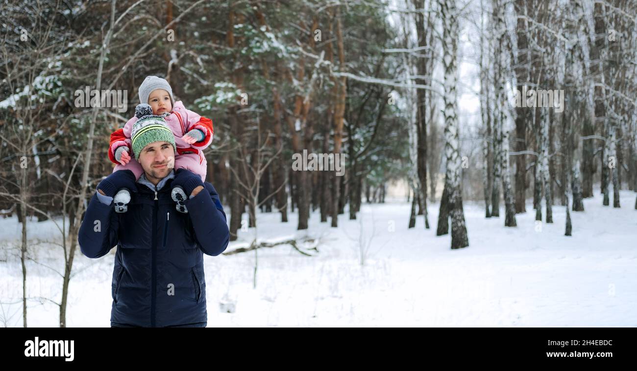 Portrait du père heureux et de la petite fille sur fond de nature d'hiver.Homme et petite fille sur ses épaules dans le parc d'hiver.Vacances de Noël Banque D'Images